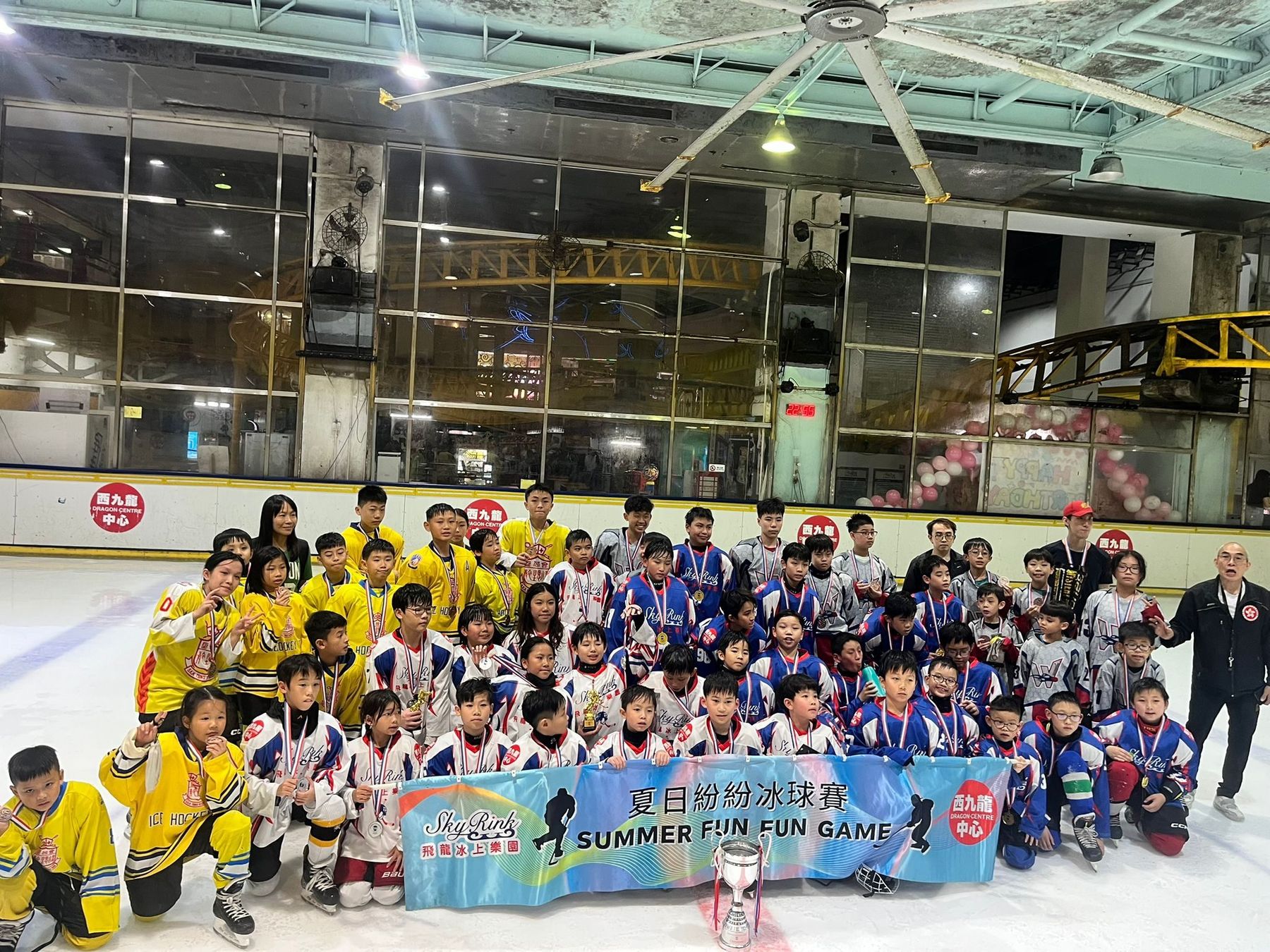 All the teams together on the ice under the Summer Fun Fun Game banner at Dragon Centre Sky Rink