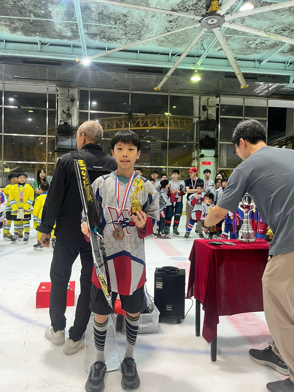 Coaches presenting the tournament trophy to a young player at centre ice
