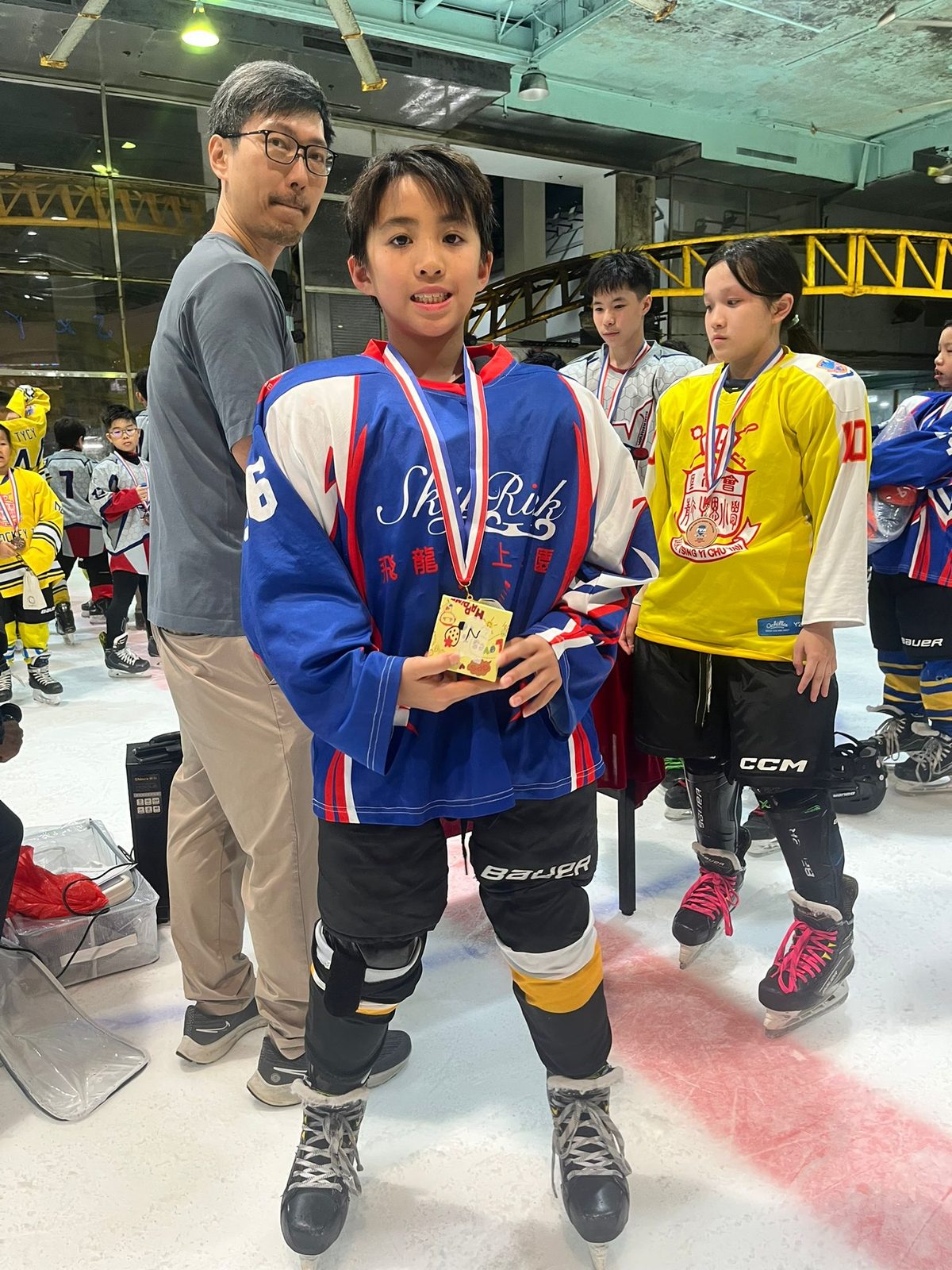 Player with his medal and prize, teammates waiting behind