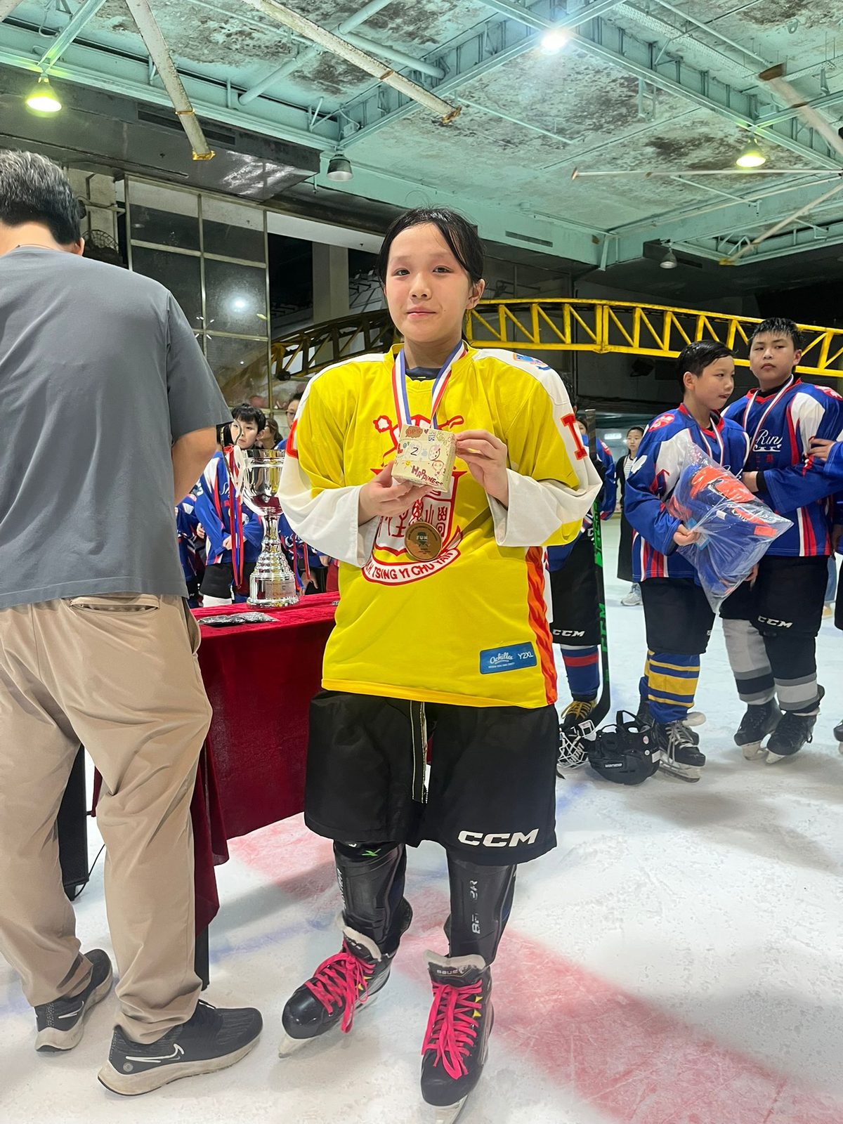 Player in a yellow jersey with her medal and prize