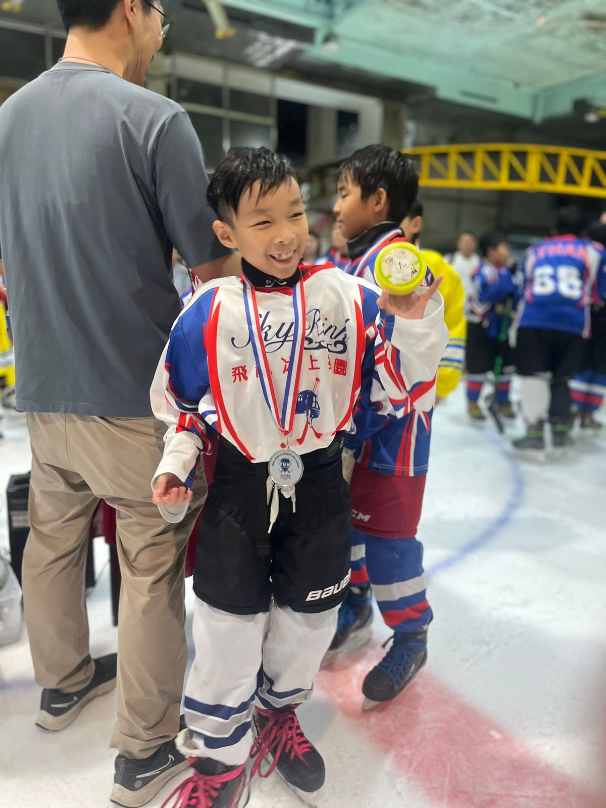 Player all smiles with his medal as the teams look on
